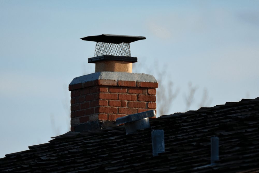 Brick chimney with cap against blue sky